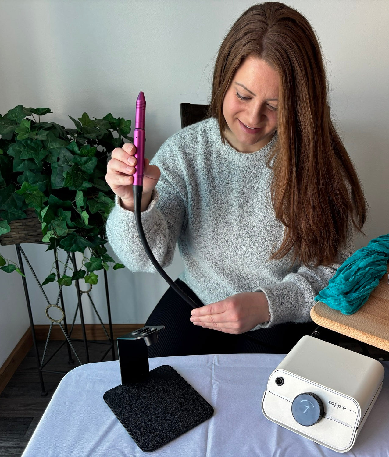 Trinity holding a permanent jewelry welder stylus
